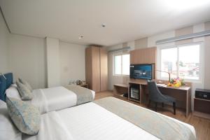 Habitación de hotel con 2 camas y escritorio con TV. en Blue Lotus Hotel, en Davao City