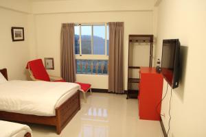 a bedroom with a bed and a tv and a window at Dapu Inn in Juguang
