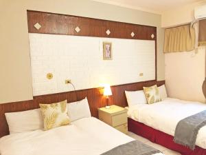 una habitación de hotel con 2 camas y una lámpara en Yun’s Homestay, en Luodong