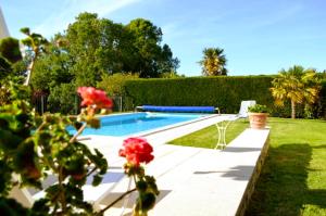 a swimming pool in a yard with roses in the foreground at Logis de Chenac - Chambres et table d'hôtes in Chenac Saint Seurin D'uzet