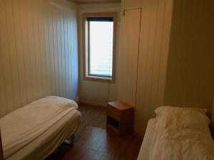 Habitación pequeña con 2 camas y ventana en Nabben Inn, en Selje