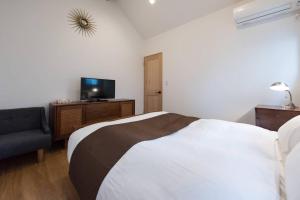 a bedroom with a bed and a tv and a chair at TOOD一宮 -B棟 in Ichinomiya