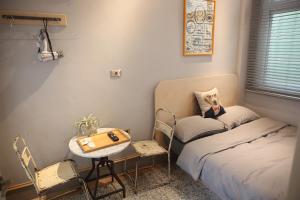 a small room with a bed and a table and chairs at Spring Guest House in Tainan