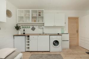 a kitchen with white cabinets and a washing machine at Apartament Trójmiejski Park Krajobrazowy in Gdańsk