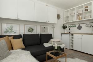 a living room with a black couch and a kitchen at Apartament Trójmiejski Park Krajobrazowy in Gdańsk