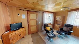 ein Wohnzimmer mit 2 Stühlen und einem Flachbild-TV in der Unterkunft Guferli in Blatten bei Naters