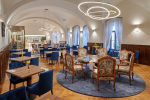 a restaurant with tables and chairs and a chandelier at Hotel Štekl in Hluboká nad Vltavou