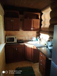 uma cozinha com armários de madeira e um micro-ondas em Pirts māja Ramatas em Skulte