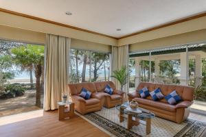 a living room with brown leather furniture and large windows at Seapine Beach Golf and Resort Hua Hin in Hua Hin