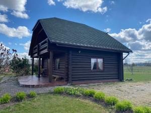 a log cabin with a deck in a field at Piešupīte in Staburags