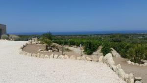 un giardino con rocce e alberi su una spiaggia di Serra Niedda Resort & Agriturismo a Sorso