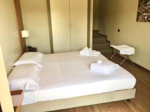 Una gran cama blanca con toallas encima. en Hotel Barrage, en Pinerolo