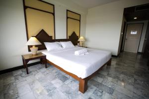 a bedroom with a large white bed with two lamps at Seeharaj Hotel in Uttaradit