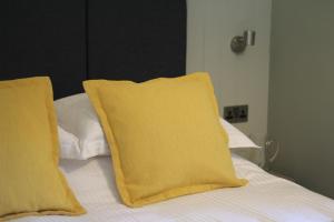 The Five Pilchards Inn في هيلستون: سرير عليه وسادتين صفراء