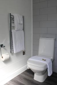 a bathroom with a white toilet and towels at The Five Pilchards Inn in Helston