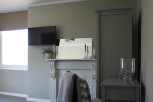 a room with a fireplace with a mirror and a chair at The Five Pilchards Inn in Helston