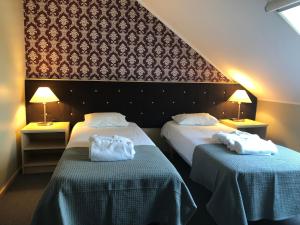 two beds in a hotel room with towels on them at von ROSEN spa in Mäetaguse