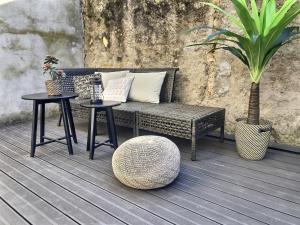 een rieten bank en twee tafels op een dek bij Le Mangin - Studio avec terrasse in Metz +4 foto's