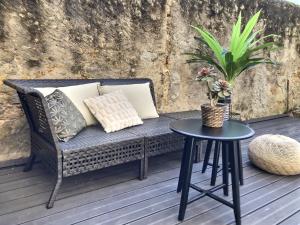 un banc en osier sur une terrasse avec une table dans l'établissement Le Mangin - Studio avec terrasse, à Metz