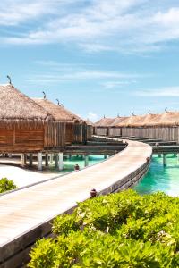 a large wooden dock with a boat in front of it at Constance Moofushi Maldives - All Inclusive in Himandhoo 