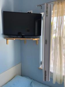 einen Flachbild-TV an einer Wand neben einem Fenster in der Unterkunft Apartman Ana in Umag