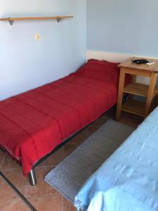 ein rotes Bett in einem Zimmer mit einem Tisch in der Unterkunft Apartman Ana in Umag