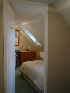 ル・コンケにあるGîtes Le Bout du Mondeのベッドルーム1室(ベッド1台付)、屋根裏部屋のドレッサー