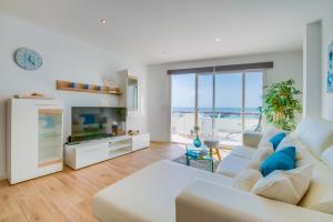 a living room with a white couch and a television at Ideal Property Mallorca - Blue Attic Beach in Alcudia +18 photos