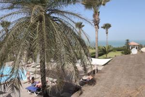 a group of people sitting under palm trees near a pool at Ocean Villa Heights in Brufut