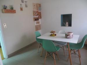 comedor con mesa blanca y sillas verdes en Villa Margarida en Viana do Castelo