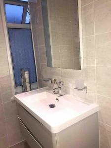 ein Badezimmer mit einem weißen Waschbecken und einem Spiegel in der Unterkunft Entire Whalley House in Burnley