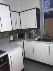 a kitchen with white cabinets and a sink at Entire Whalley House in Burnley