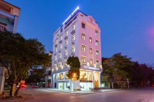 wysoki różowy budynek na ulicy miejskiej w nocy w obiekcie Victoria Hotel Ninh Binh w mieście Ninh Binh
