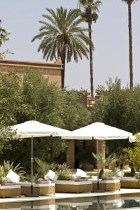 a patio area with umbrellas and palm trees at Hotel Les Cinq Djellabas in Douar Caïd Layadi