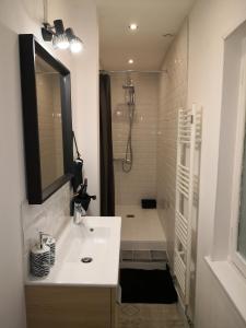 y baño blanco con lavabo y ducha. en Chez Lilas 150m Plage, en Dunkerque