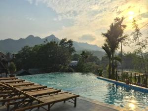 a swimming pool with chairs and mountains in the background at Mai Chau Green Rice Field Hotel in Mai Châu