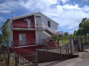 a red and white house with a fence at Airport home Radinovic in Podgorica