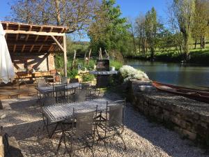 a patio with tables and chairs next to a river at Ancien moulin Créancey in Créancey