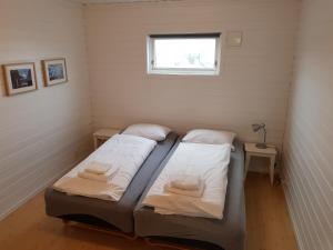 Utsira Overnatting - Sildaloftet في Utsira: سريرين في غرفة صغيرة مع نافذة