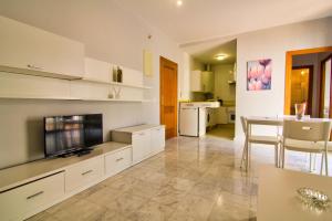 a kitchen with white cabinets and a dining room with a table at Apartamentos Centro 1 El Puerto de Santa Maria in El Puerto de Santa María