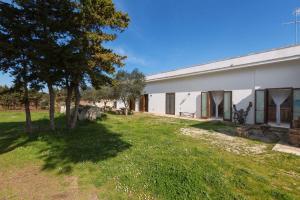 un bâtiment blanc avec un arbre et une pelouse dans l'établissement Agriturismo Podere San Giorgio, à Otrante