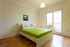 a bedroom with a bed with a green blanket on it at Apartment Partizanska in Ohrid