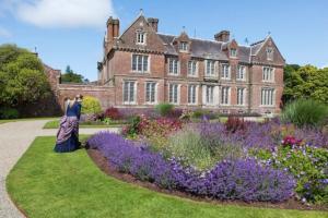 une femme debout devant une maison avec des fleurs dans l'établissement Self Catering - Gardeners Cottage, à Wexford