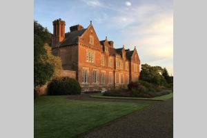 - un grand bâtiment en briques avec une pelouse dans l'établissement Self Catering - Gardeners Cottage, à Wexford