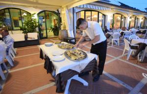 Un uomo che prepara un piatto di cibo su un tavolo di Hotel Belmare a Marciana