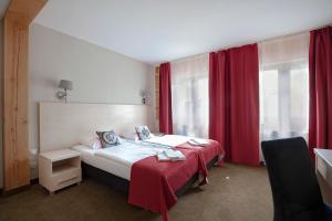 a hotel room with a bed and red curtains at Karczma Czarna Góra - Czarna Góra Resort in Stronie Śląskie