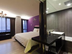 a bedroom with a bed and a bathroom with a sink at FX Hotel Taipei Nanjing East Road Branch in Taipei