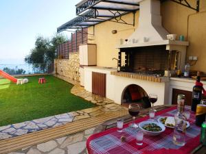 Villa Artemis في برباتي: فناء مع طاولة مع كؤوس للنبيذ عليه مع بيتزا
