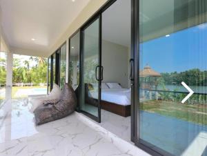 a bedroom with a bed and a large glass window at Suan Son Villa Koh Sa Nher สวนสนธิ์วิลล่า เกาะเสนอ SHA in Surat Thani +46 photos
