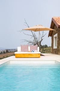 una piscina con ombrellone e due sedie e un tavolo di Quinta do Cedro Verde ad Armamar Altre 4 foto